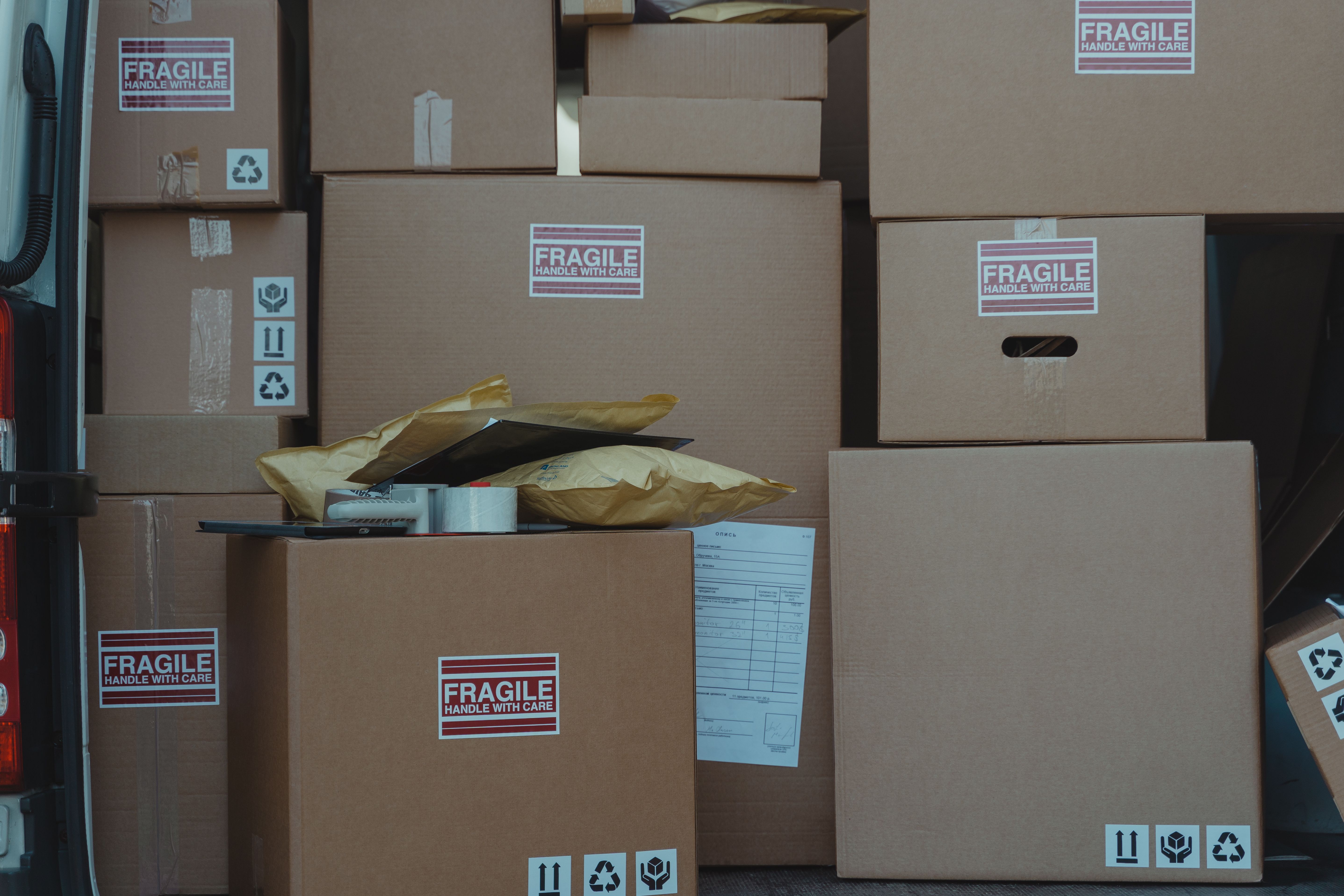 Variety of cardboard boxes labeled fragile stacked in a vehicle ready for shipping