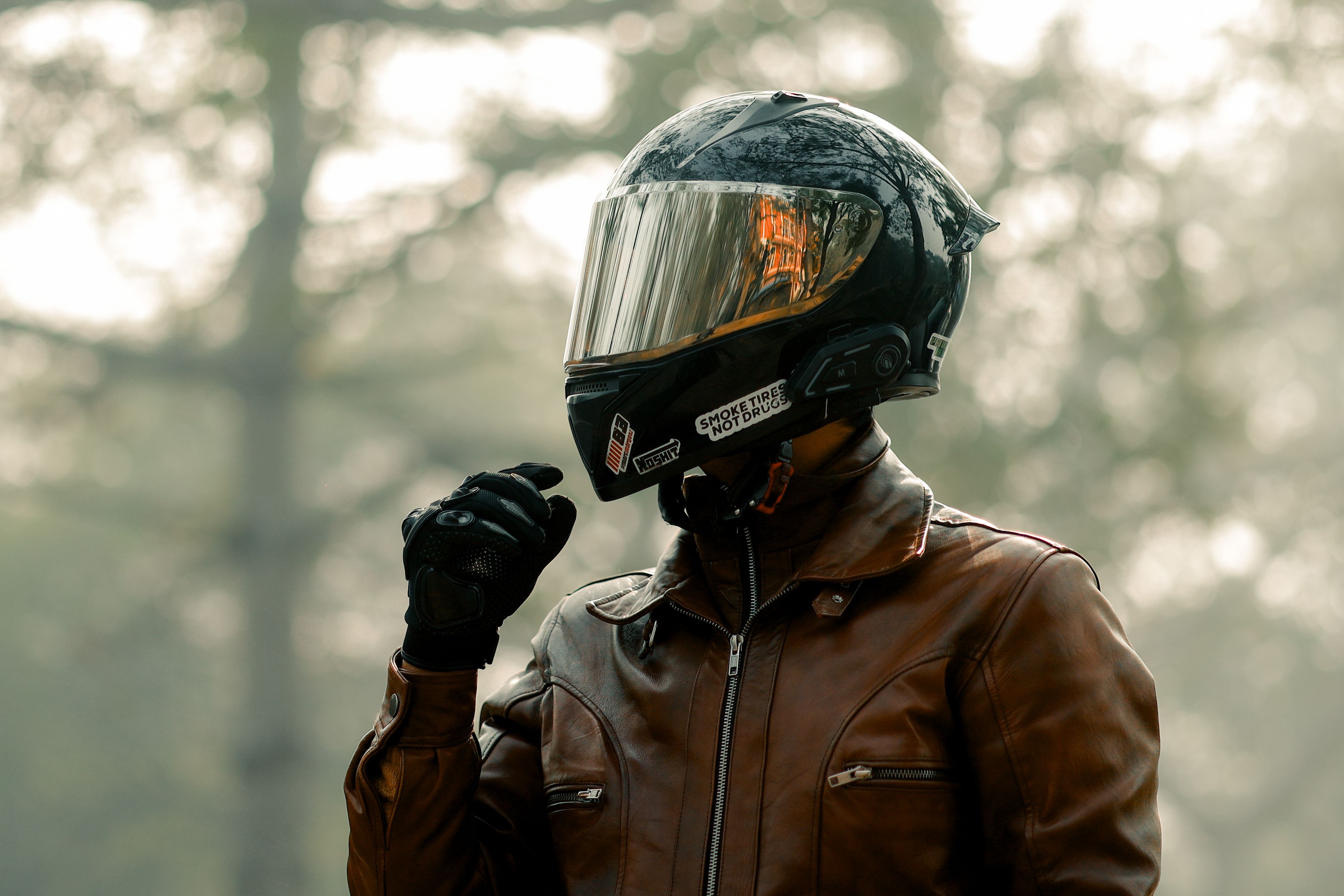 Biker wearing helmet and jacket riding through a foggy forest in cold wind
