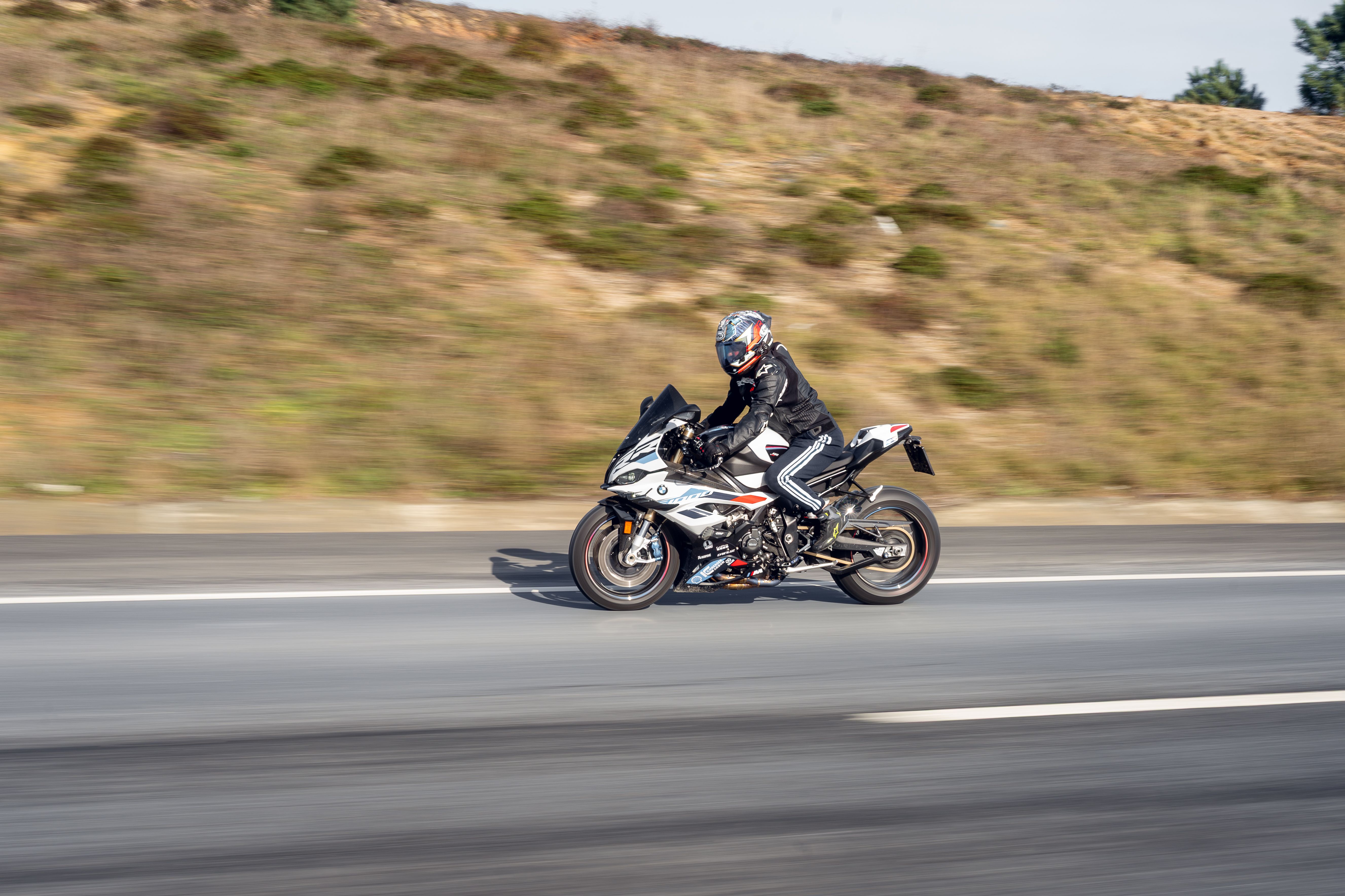 Motorcyclist wearing helmet riding a sports bike on an open highway exposed to wind
