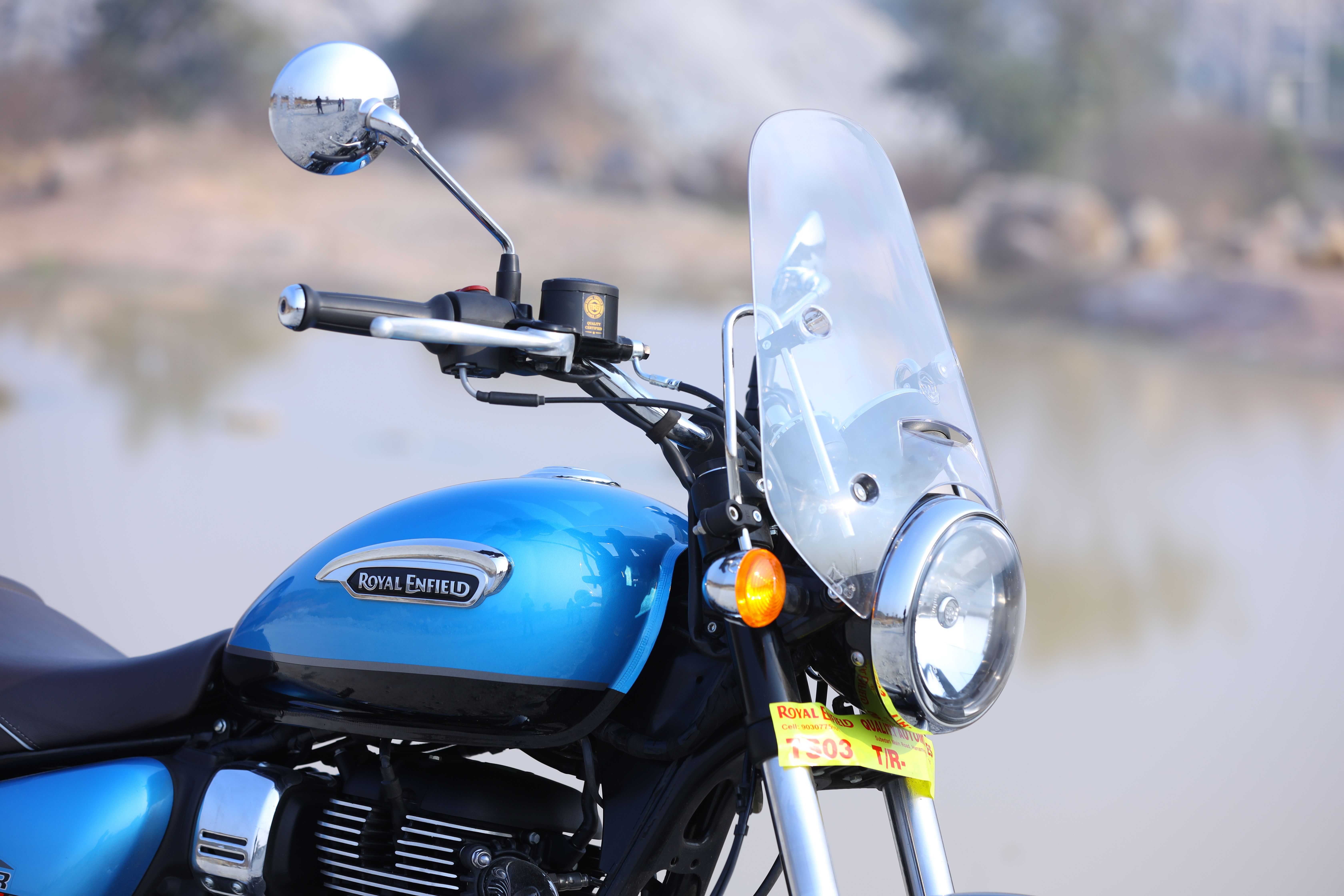 Blue Royal Enfield motorcycle with headlight and tall windscreen outdoors