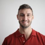 Smiling man giving a warm, approachable first impression in a simple portrait.