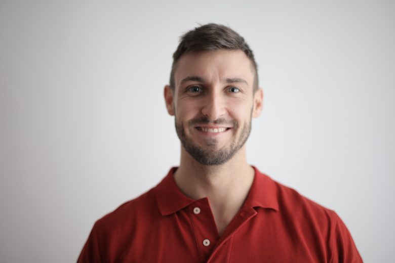 Smiling man giving a warm, approachable first impression in a simple portrait.