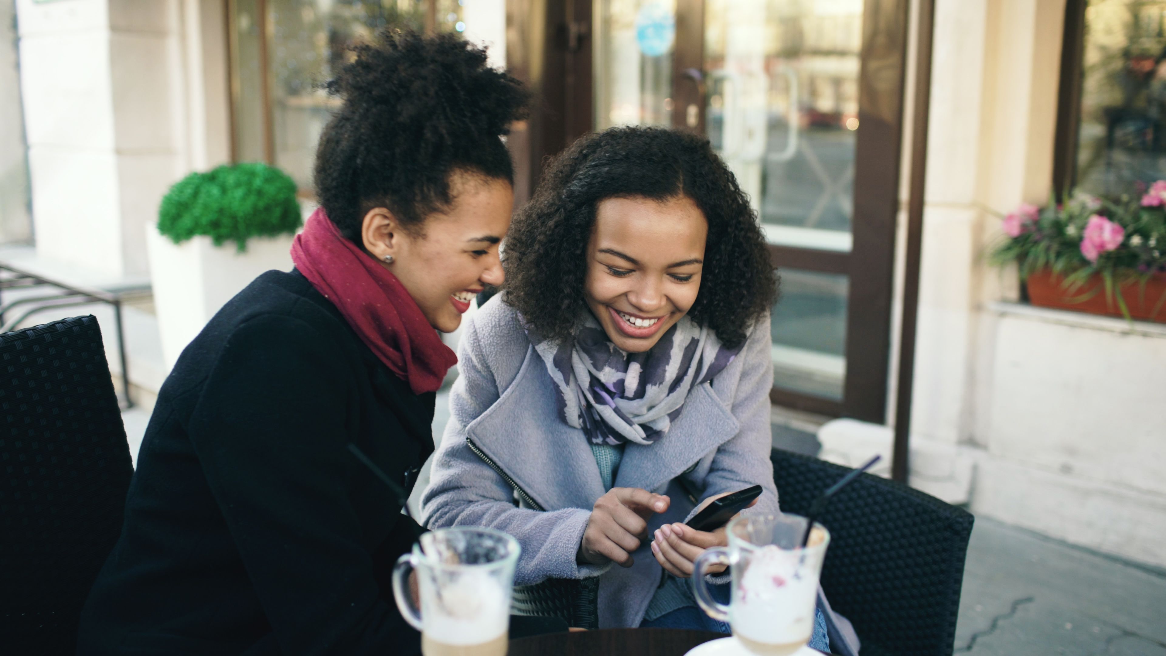 Two friends laughing together over coffee, showing positive social connection and rapport.